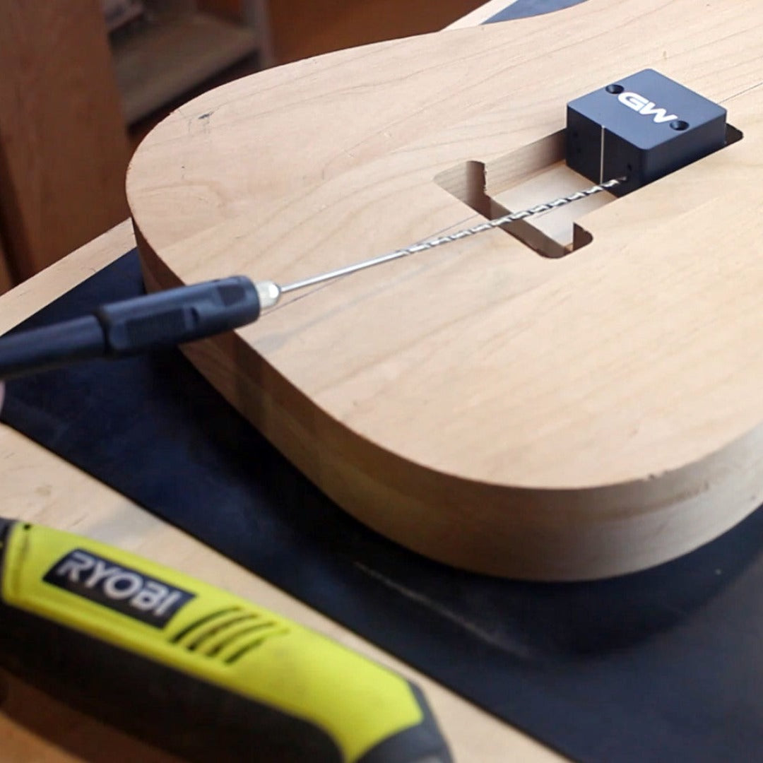 bottom of a guitar getting repaired with a jig and drill