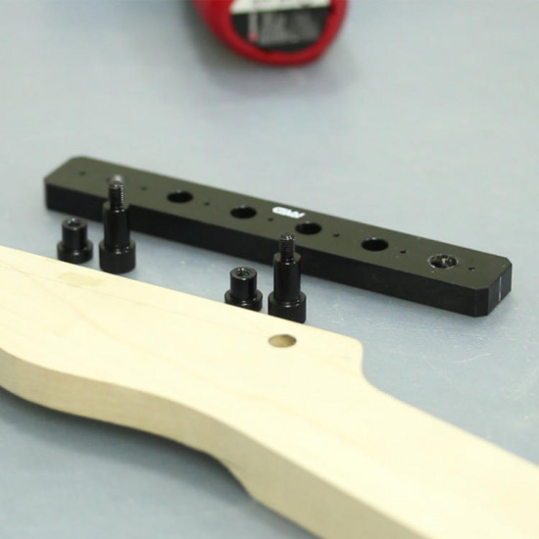 Tuner Drilling Jig next to guitar with 2 screws