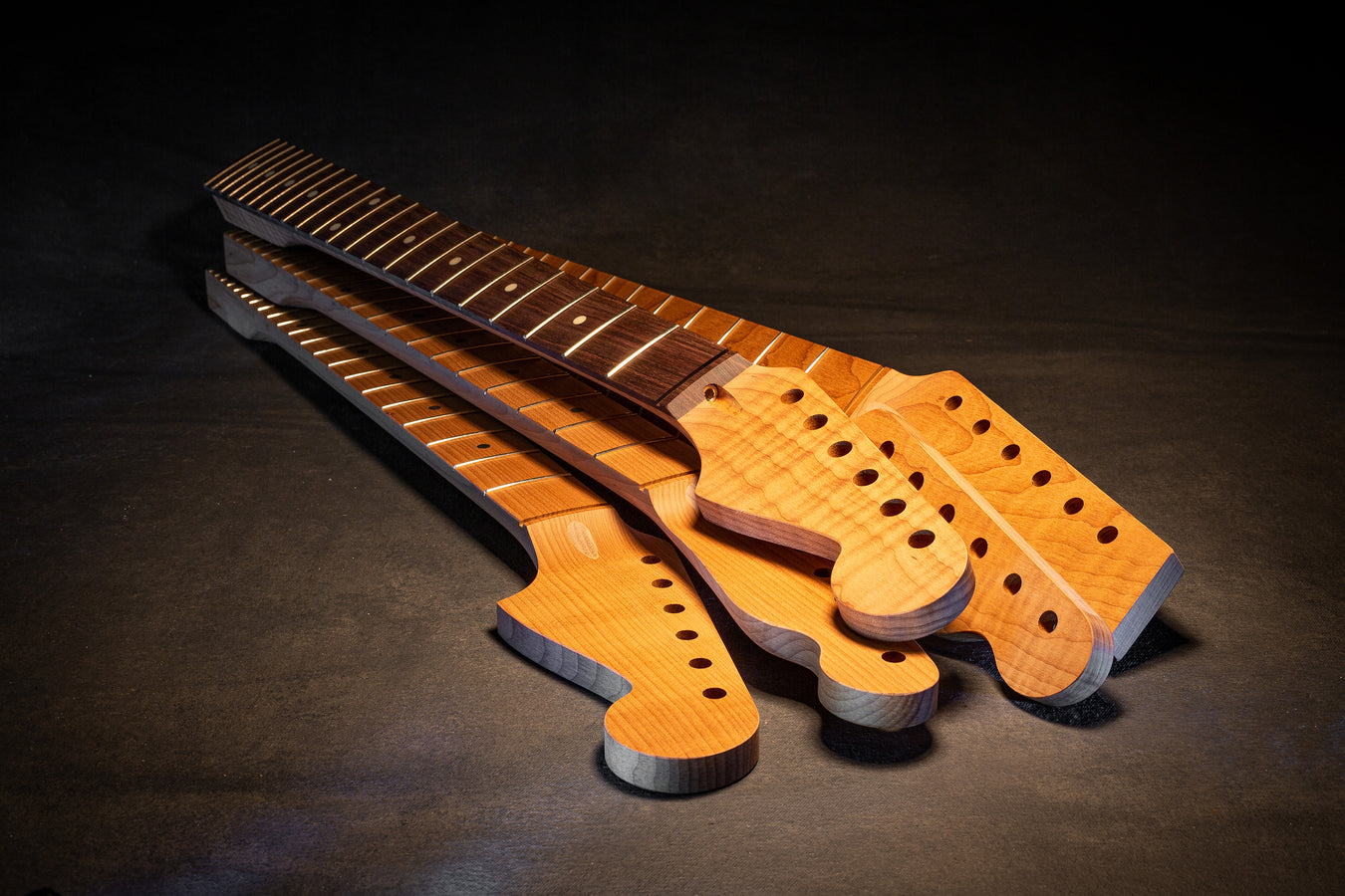 stack of wood colored unfinished guitar necks
