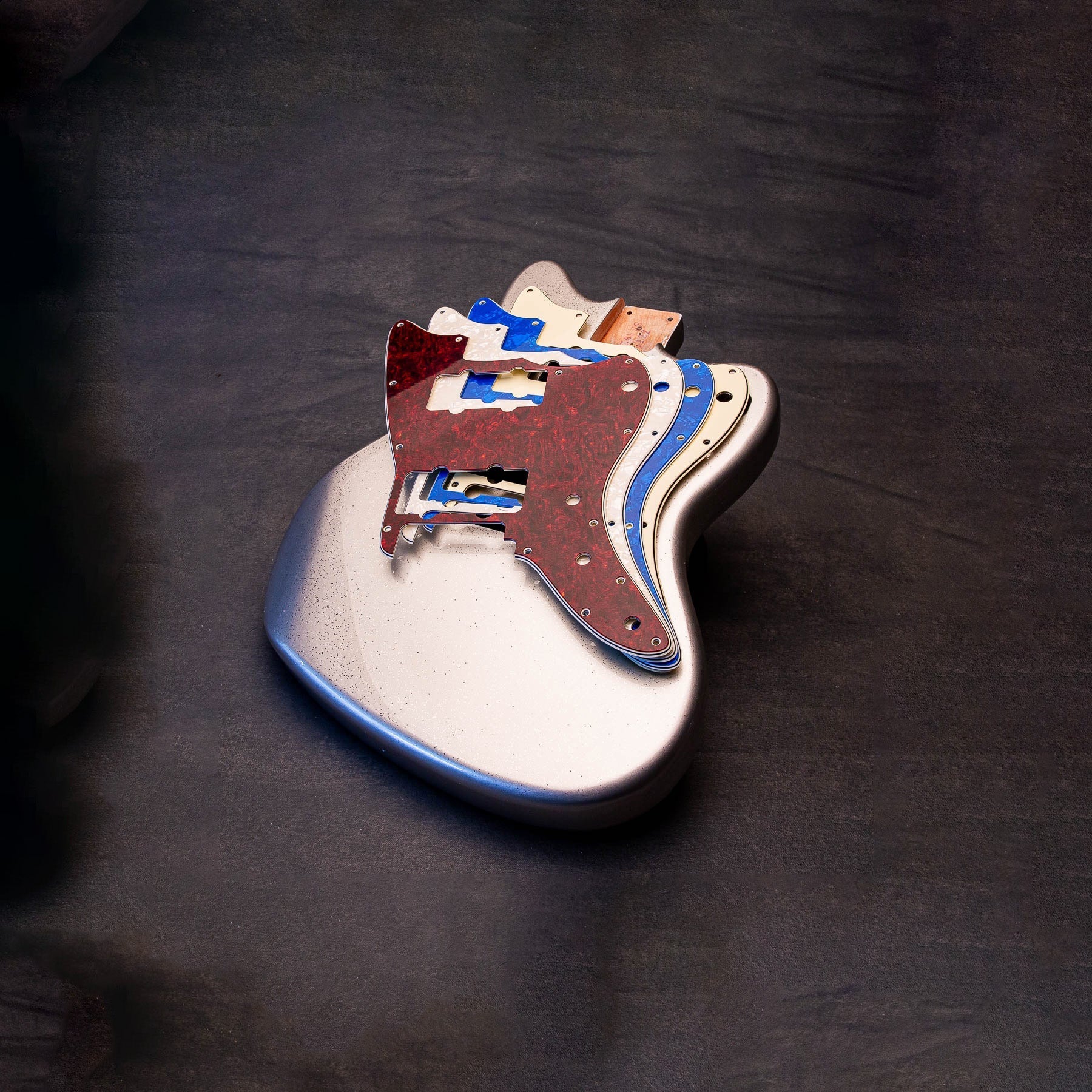 a guitar with lots of multi colored pickguards stack on top