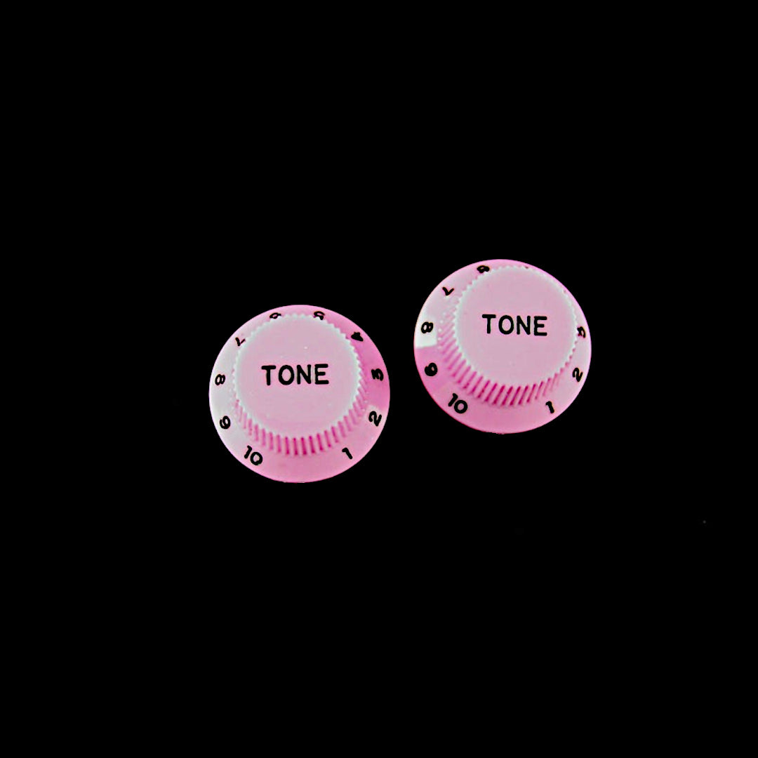 two pink strat knobs with the word "tone"