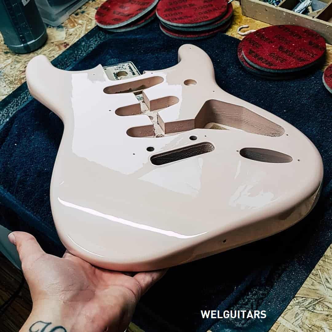 shell pink spray painted guitar on work table