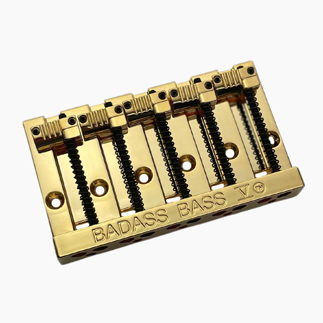 gold angled view of 5-string bass bridge with grooved saddles